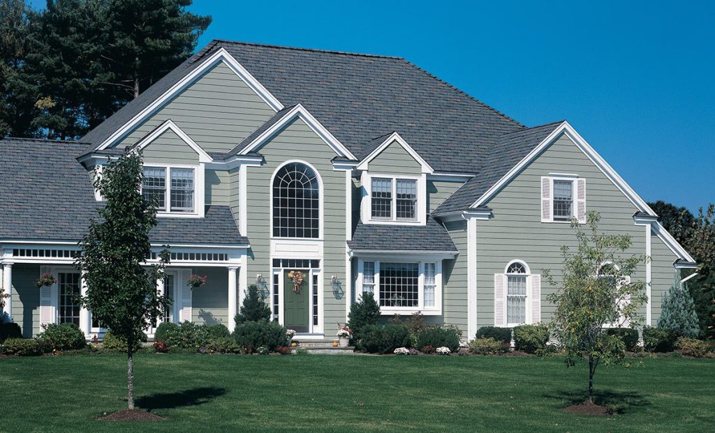 Large gray two-story house with white trim and a well-kept lawn.