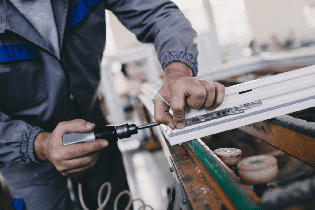 Worker assembling a window frame with drill.