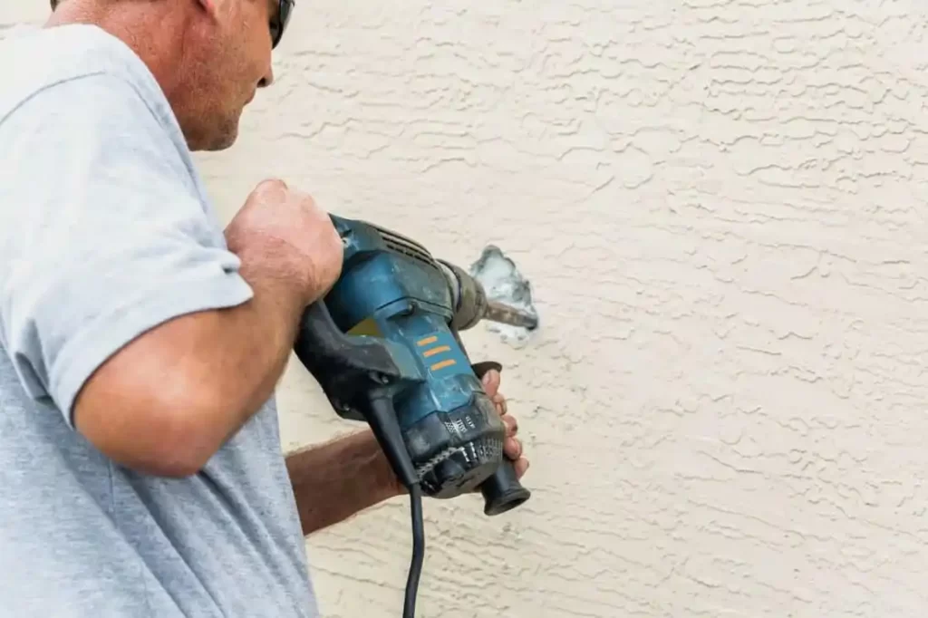 Man using drill on textured wall.