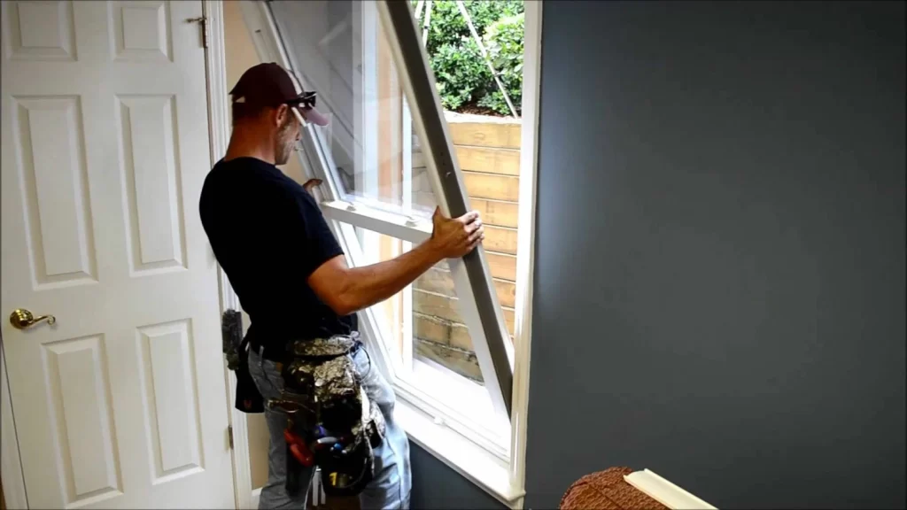 Worker installing a window frame indoors.