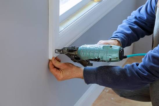 Person using a power drill to install a white windowsill.